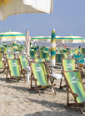 Spiaggia sabbiosa con lettini e ombrelloni colorati sotto il sole.