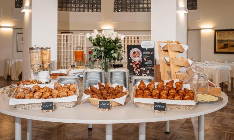 Buffet di colazione con croissant e cereali in un ambiente elegante.