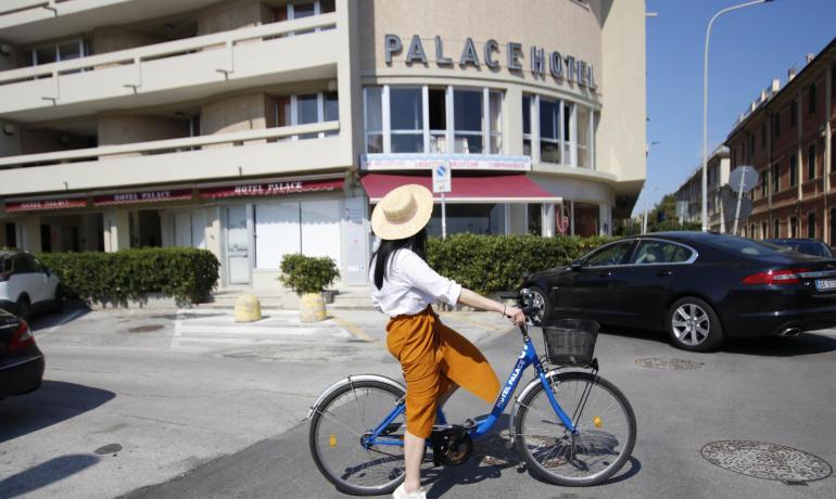 Donna in bici davanti al Palace Hotel.