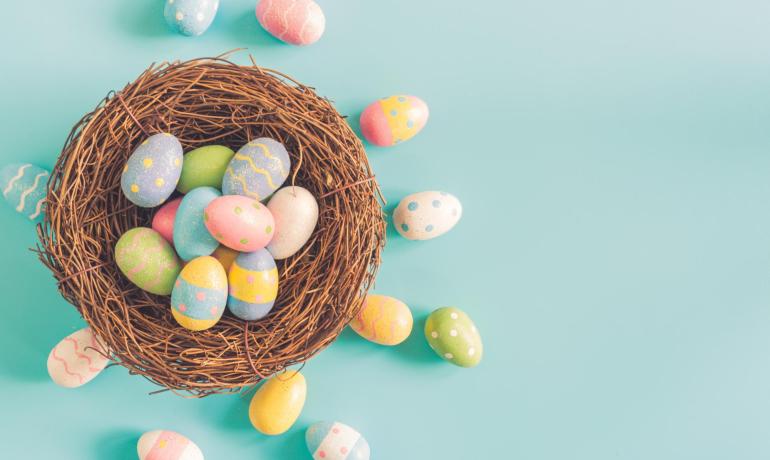 Nido con uova di Pasqua colorate su sfondo azzurro.