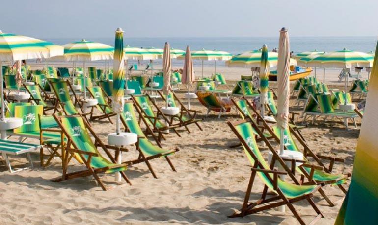 Spiaggia con ombrelloni e sdraio colorati, vista mare.