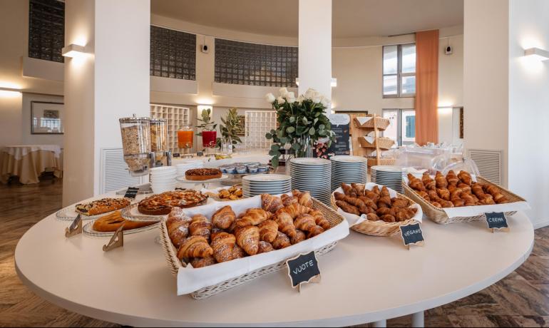 Buffet con croissant, dolci e succhi in un ambiente elegante.