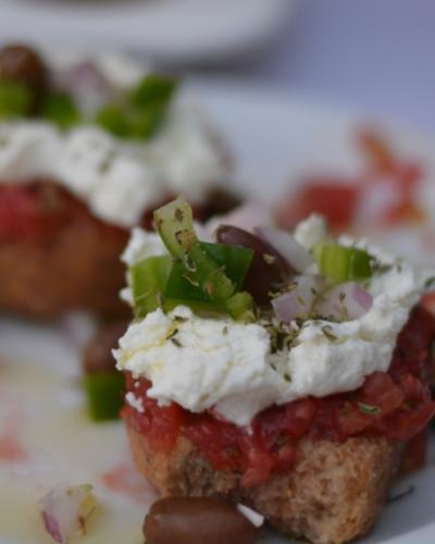 Bruschetta con formaggio cremoso, pomodoro, olive e peperoni.