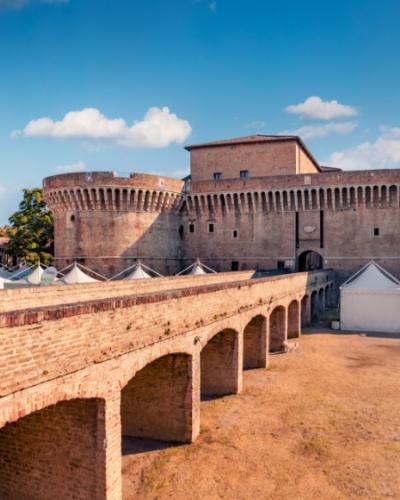 Antica fortezza con mura in mattoni e torri, sotto un cielo sereno.