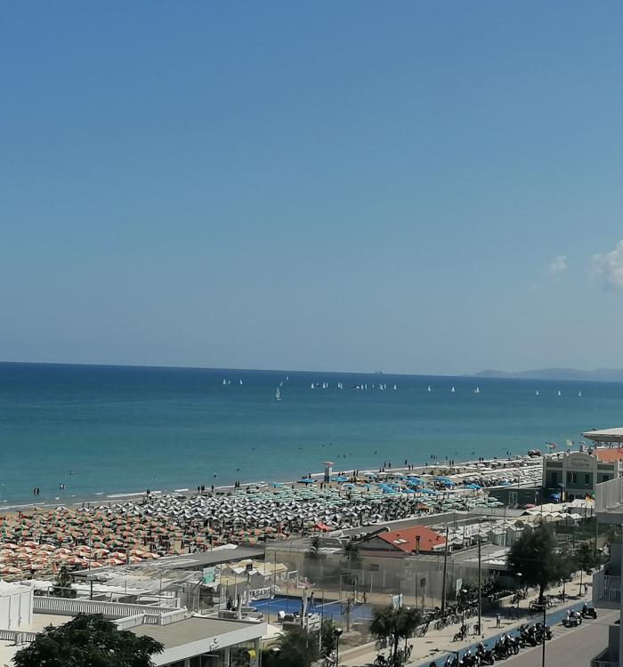 Spiaggia affollata con ombrelloni colorati e mare calmo, vista panoramica.