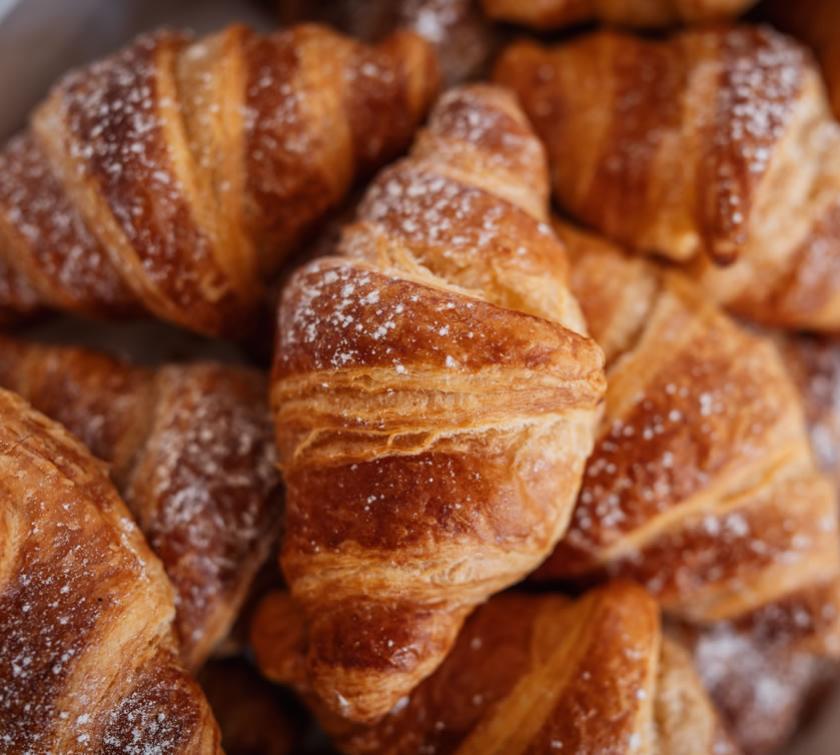 Croissant dorati con zucchero a velo, perfetti per una colazione deliziosa.