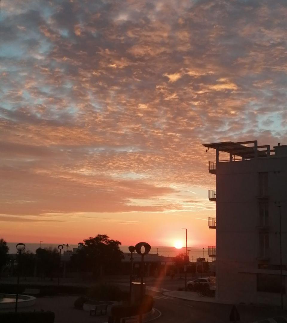 Tramonto suggestivo con cielo nuvoloso e silhouette di un edificio moderno.