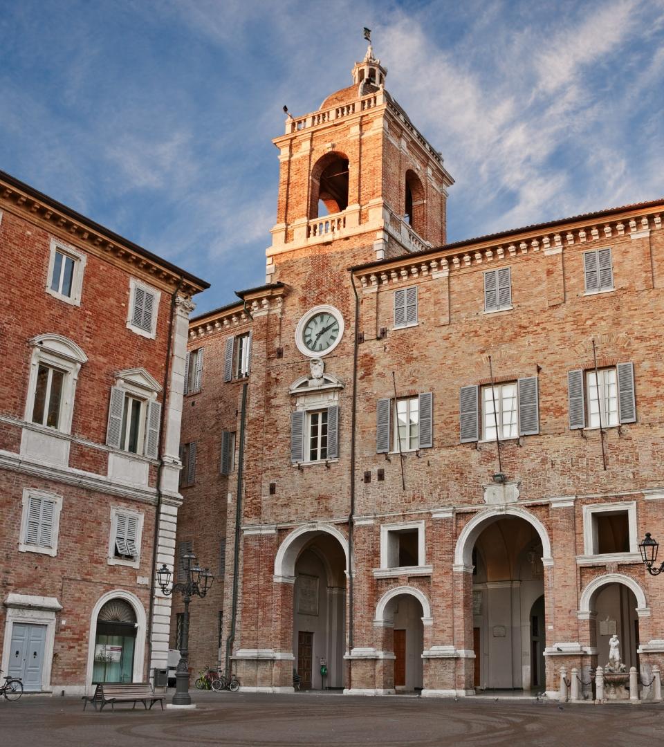 Edificio storico con torre dell'orologio in una piazza cittadina.