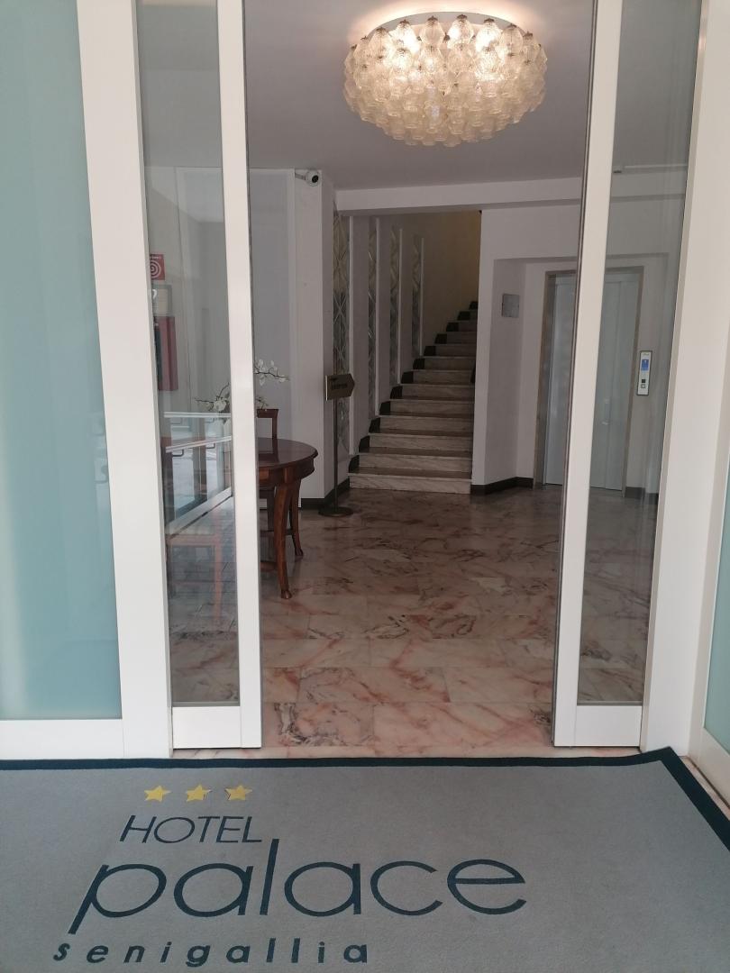 Ingresso dell'Hotel Palace Senigallia con tappeto e lampadario elegante.